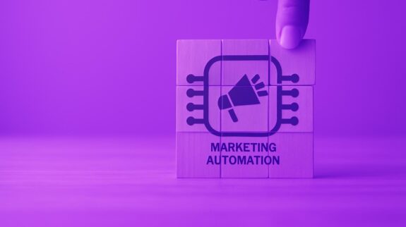 Xây Dựng Dịch Vụ Tự Động Hóa Marketing Từ khóa hình ảnh: ghép hình các viên gỗ với biểu tượng máy tính và loa tích hợp, biểu tượng về tự động hóa marketing và trí tuệ nhân tạo, phù hợp với nội dung về công nghệ tự động hóa marketing của VAQ Digital.