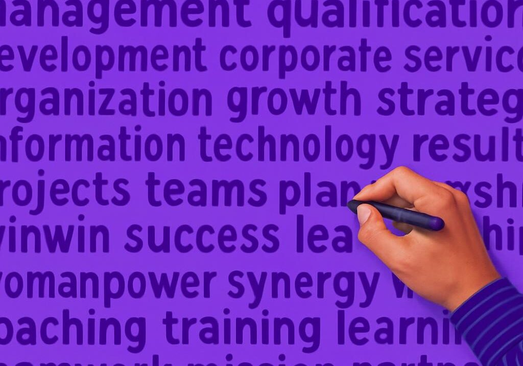 Xây Dựng Chiến Lược Marketing Hiệu Quả Bàn tay cầm bút viết lên các thuật ngữ kinh doanh, minh họa cho việc lập một chiến lược marketing online hiệu quả.