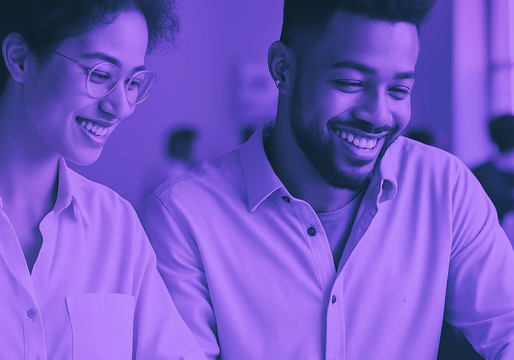 Hai chuyên gia content marketing, một nam và một nữ, đang mỉm cười vui vẻ khi làm việc cùng nhau trên một dự án.